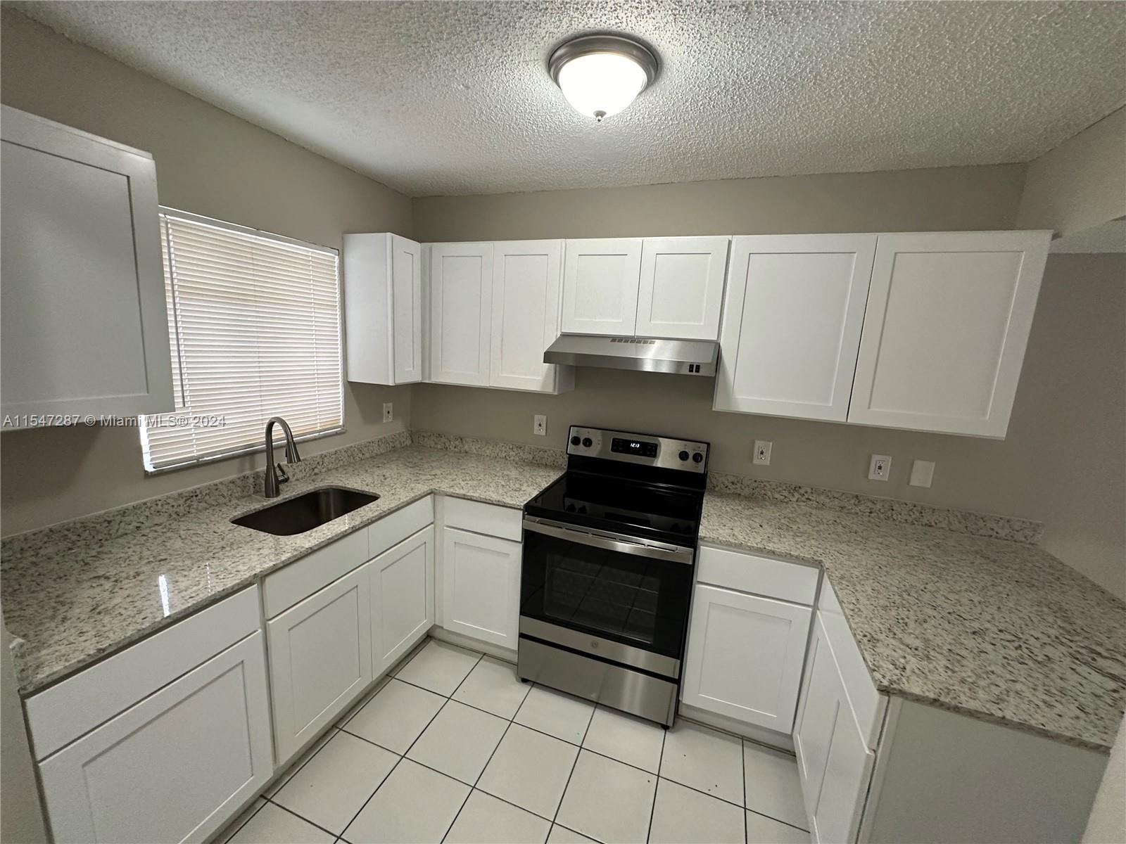 3051 West 76th Street, Unit D211 Hialeah, FL 33018 - Photo 9 of 22 a kitchen with granite countertop white cabinets and appliances