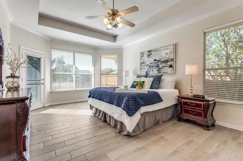 a spacious bedroom with a bed painting on wall and windows