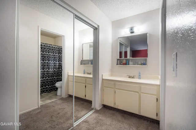 a spacious bathroom with a shower a sink and a mirror