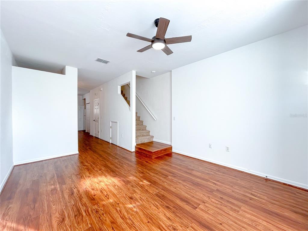 3575 Southwest 30th Way, Unit 119 Gainesville, FL 32608 - Photo 2 of 11 a view of an empty room with wooden floor and a ceiling fan