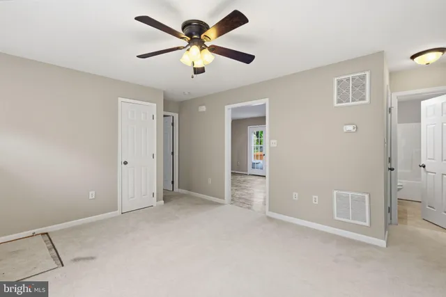 an empty room with chandelier fan and windows
