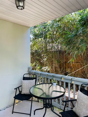 a balcony with table and chairs and potted plants