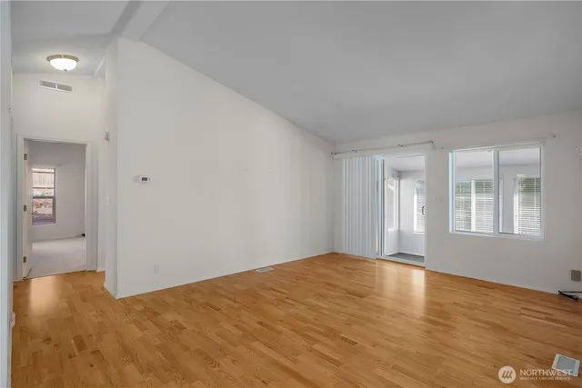 a view of an empty room with a window and wooden floor