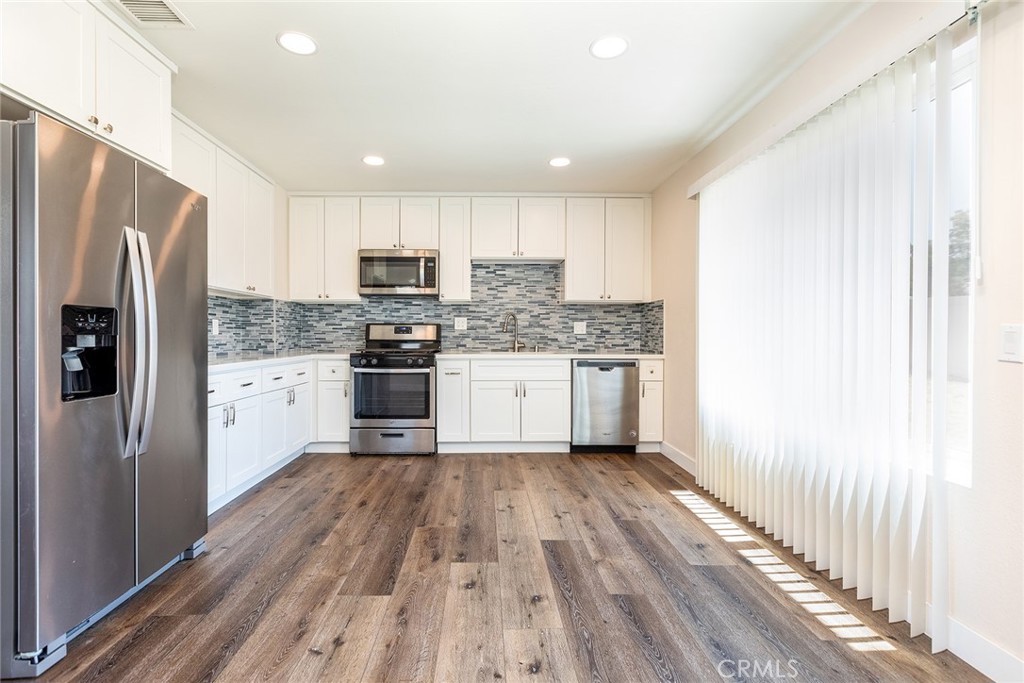 41134 Vía Halcon Temecula, CA 92591 - Photo 8 of 28 a kitchen with stainless steel appliances a refrigerator a sink dishwasher a stove and white cabinets with wooden floor