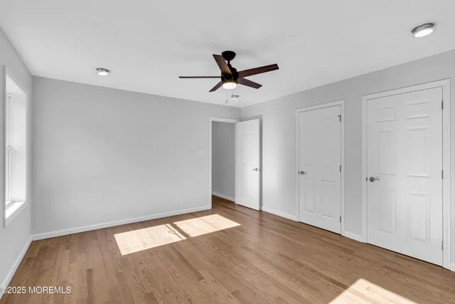 a view of room with hardwood floor and a ceiling fan