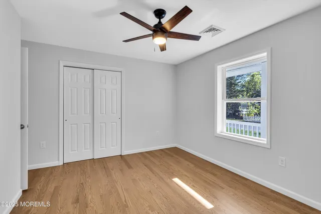 a view of an empty room with window and wooden floor