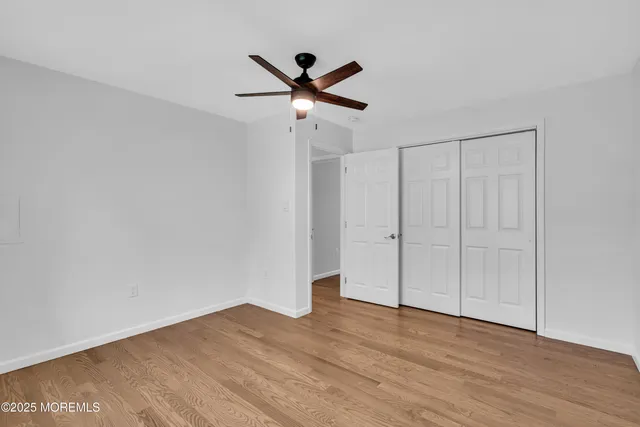 a view of empty room with wooden floor and ceiling fan