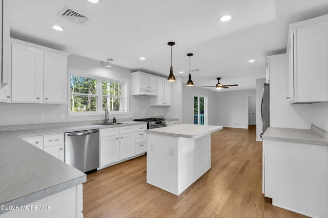 a large kitchen with cabinets wooden floor and stainless steel appliances