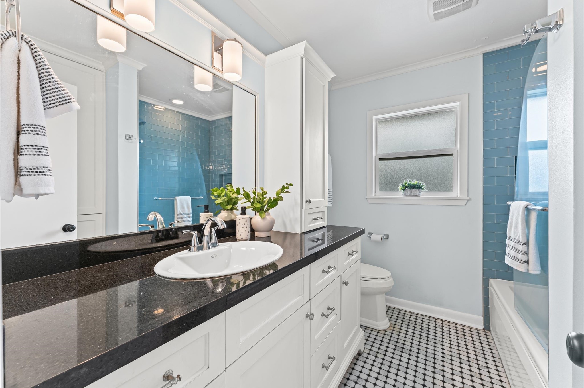 1219 Candlelight Lane Houston, TX 77018 - Photo 5 of 36 The hall bath has a timeless, refreshed feel with glass subway tile at the tub, vintage-style octagon floors, and custom cabinetry. Granite countertops tie it all together with a clean, classic look. Adjacent to two secondary bedrooms.