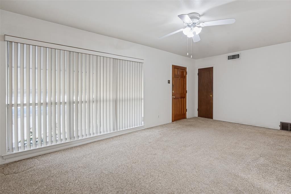 2528 Rugby Lane Farmers Branch, TX 75234 - Photo 3 of 12 Spacious room with light-colored carpet, white walls, and a large window with vertical blinds