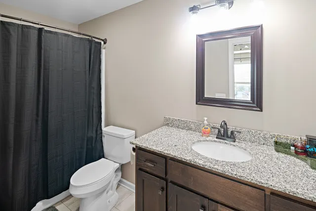 a bathroom with a granite countertop sink toilet and mirror
