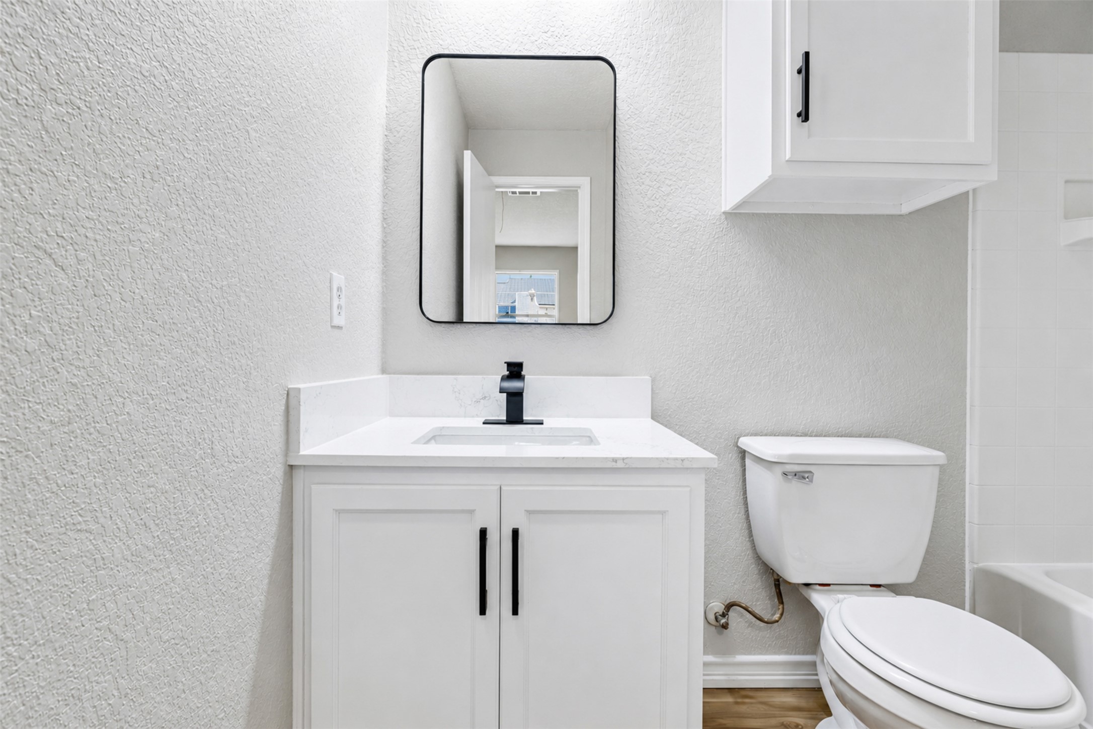 4523 Secure Lane Austin, TX 78725 - Photo 35 of 40 A well-lit bathroom showcases a pristine white vanity with sleek black hardware and a modern faucet.