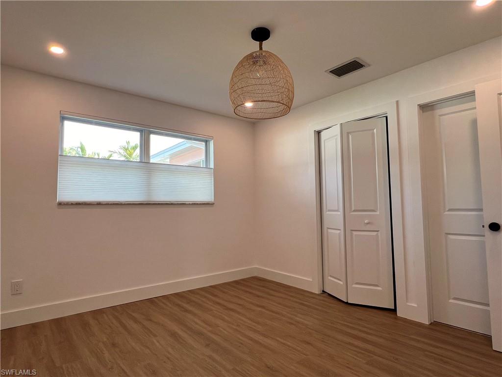 1793 Smugglers Cove, Unit B Naples, FL 34112 - Photo 15 of 23 an empty room with wooden floor and windows