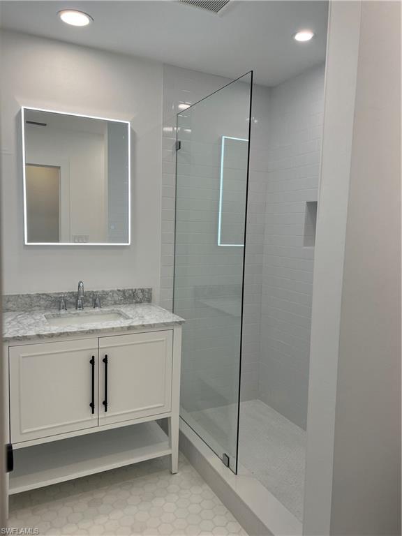 1793 Smugglers Cove, Unit B Naples, FL 34112 - Photo 18 of 23 a bathroom with a granite countertop sink a mirror and a shower