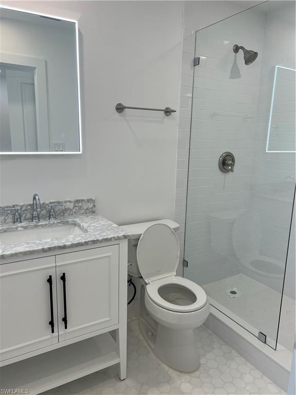 1793 Smugglers Cove, Unit B Naples, FL 34112 - Photo 19 of 23 a bathroom with a granite countertop toilet a sink and shower