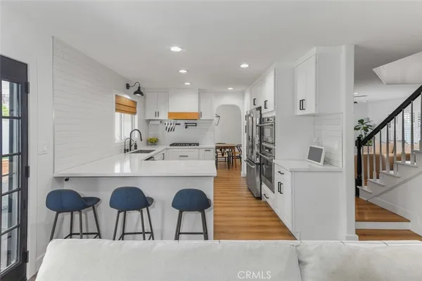 a kitchen with stainless steel appliances kitchen island granite countertop a table chairs and a refrigerator