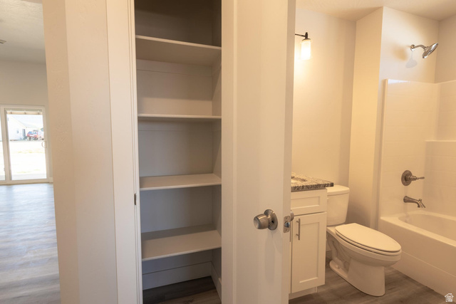 910 East Remington Road Cedar City, UT 84721 - Photo 12 of 29 Built-in linen closet featuring multiple shelves, a single vanity with a stone-finish countertop, white cabinetry, a toilet, and a bathtub with shower fixture