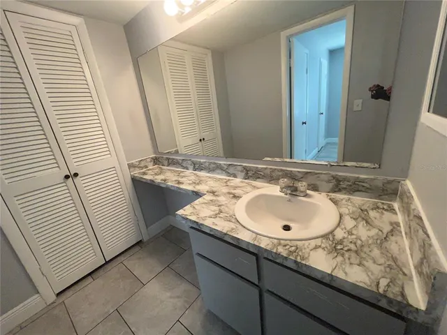 a bathroom with a granite countertop sink a light fixture and a mirror