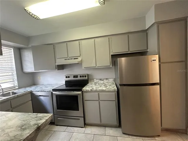 a kitchen with a refrigerator sink stove and cabinets
