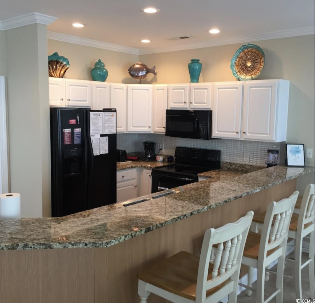 511 Caribbean Way Myrtle Beach, SC 29577 - Photo 6 of 17 Kitchen featuring stone counters, decorative backsplash, white cabinetry, crown molding, and black appliances