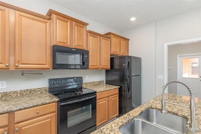 a kitchen with granite countertop a refrigerator stove and microwave