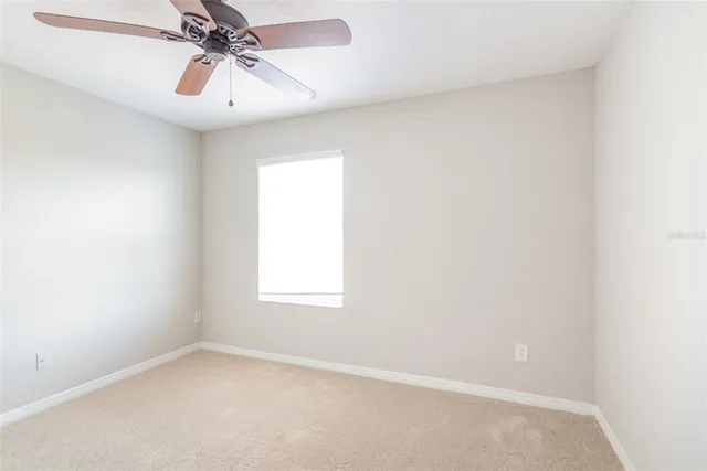 an empty room with a window and a fan