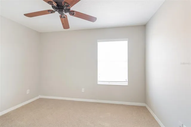 an empty room with a window and a fan