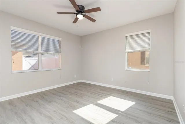 a view of empty room with wooden floor and fan