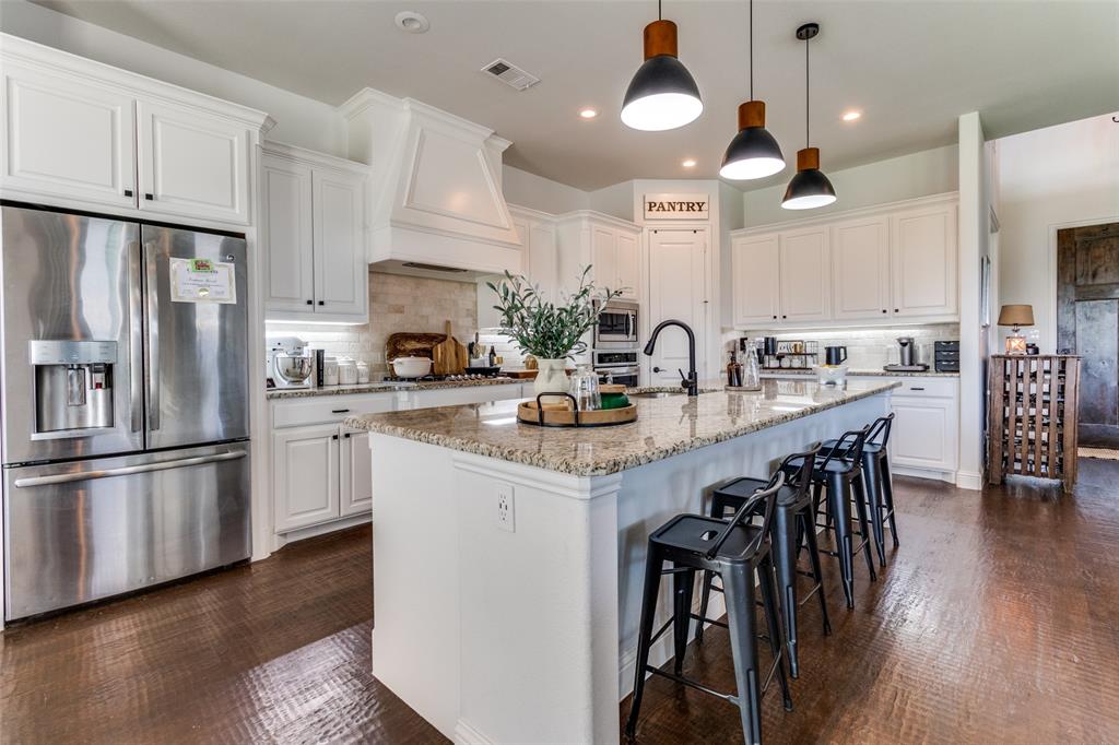 a kitchen with stainless steel appliances granite countertop a refrigerator a stove a sink dishwasher a oven with white cabinets and wooden floor
