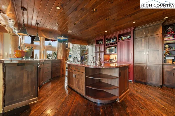 a kitchen with stainless steel appliances kitchen island granite countertop a large cabinets a sink and wooden floors