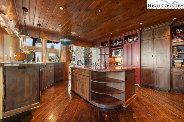 a kitchen with stainless steel appliances kitchen island granite countertop a large cabinets a sink and wooden floors