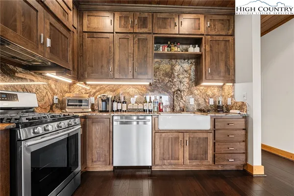 a open kitchen with stainless steel appliances granite countertop a wooden table and chairs