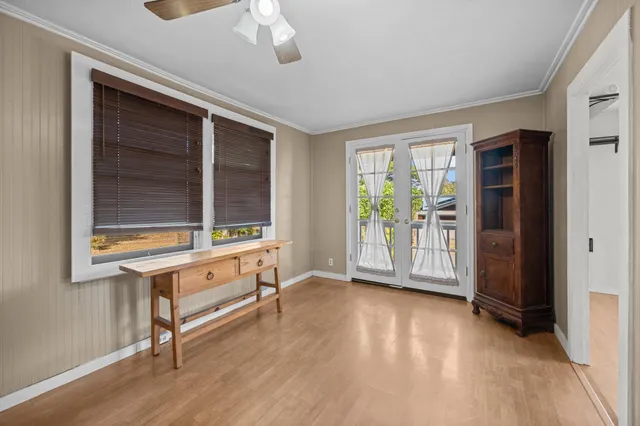 a view of an empty room with a window and wooden floor