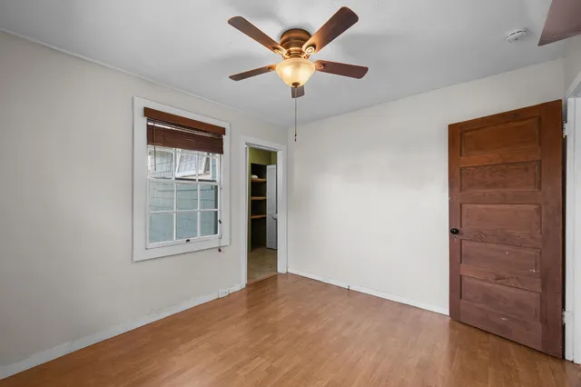 an empty room with windows and ceiling fan