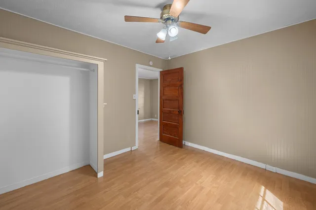 an empty room with closet and a ceiling fan