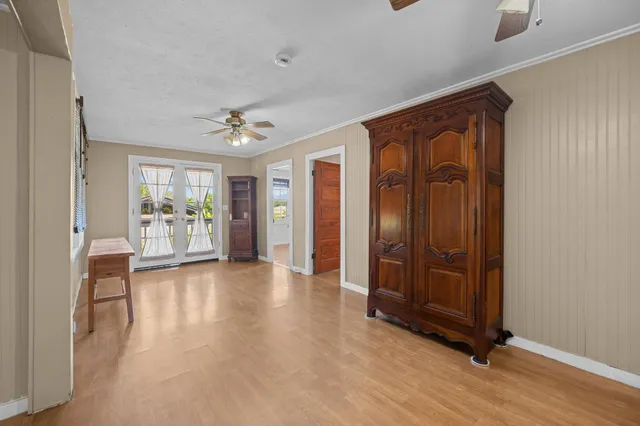 an empty room with wooden floor and a ceiling fan