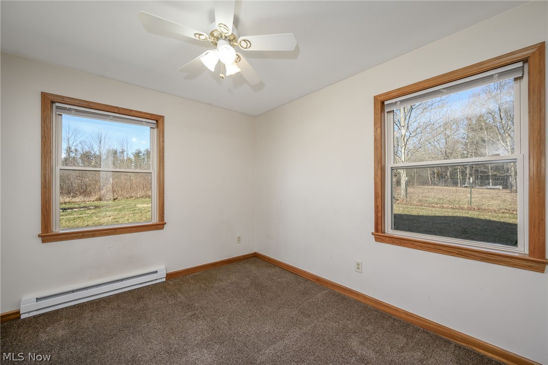 8464-8446 Tallmadge Road Diamond, OH 44412 - Photo 17 of 39 Empty room featuring a baseboard radiator, carpet floors, and ceiling fan
