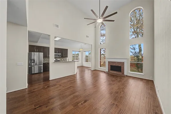 a view of a livingroom with a fireplace a ceiling fan and wooden floor