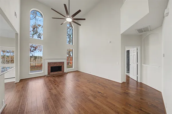 an empty room with wooden floor fireplace and windows