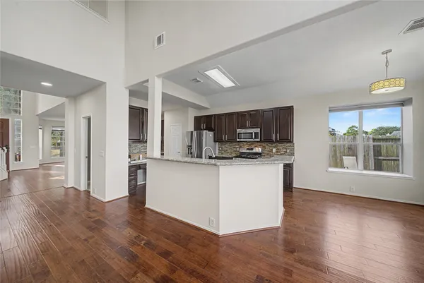 a kitchen with stainless steel appliances kitchen island wooden floors and white cabinets
