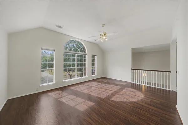 a view of an empty room with wooden floor and a window