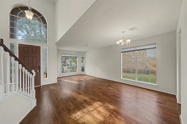 an empty room with wooden floor fan and windows