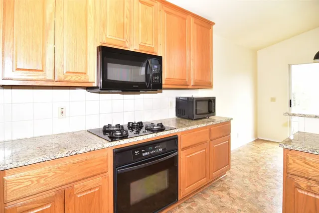 a kitchen with stainless steel appliances granite countertop a stove a sink and a microwave