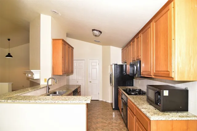 a kitchen with granite countertop a stove a sink dishwasher and a refrigerator with wooden floor