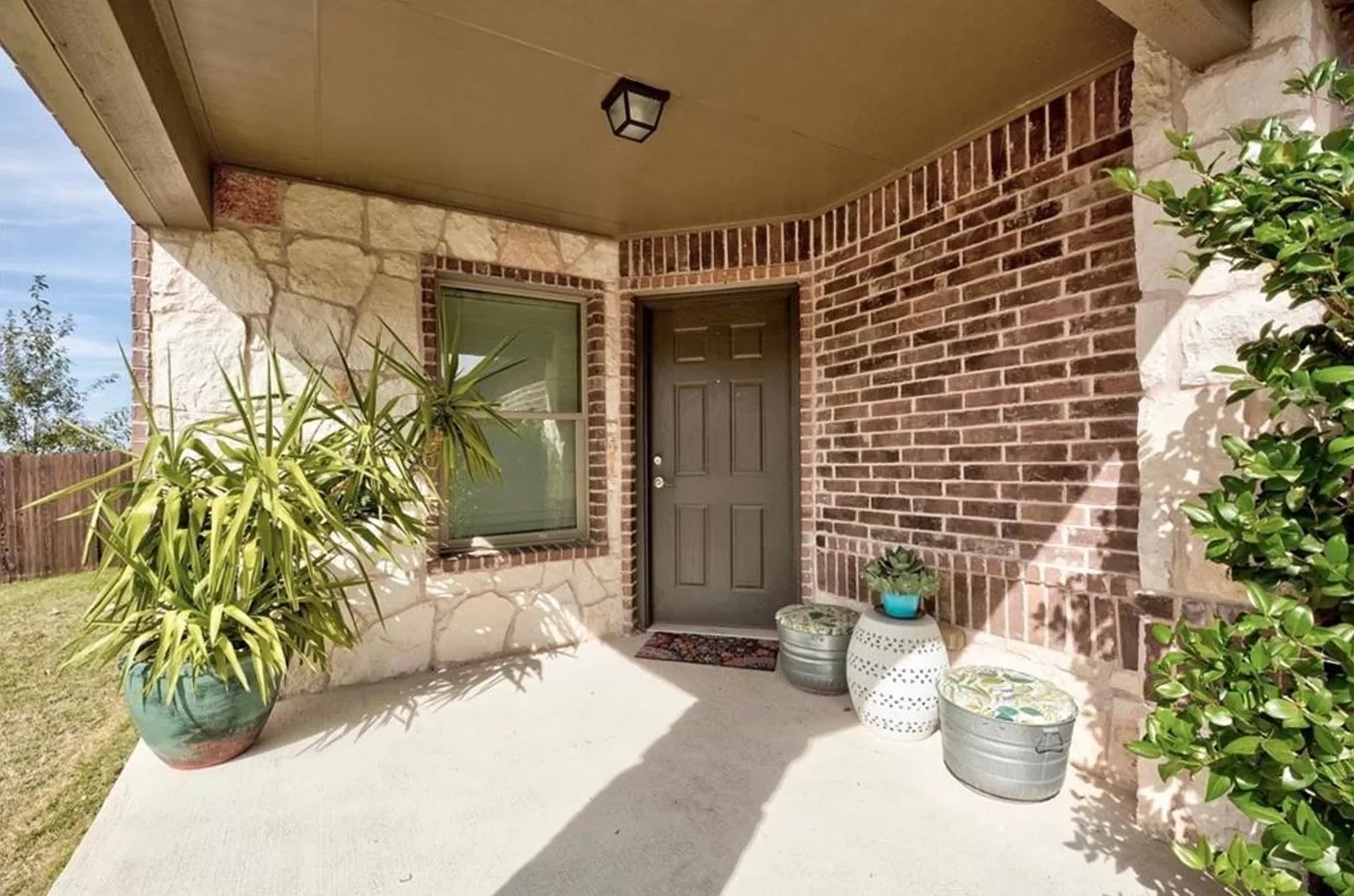 9016 Ridgewell Road Austin, TX 78747 - Photo 2 of 30 An inviting front entry features rich brickwork and natural stone accents, complemented by leafy greenery.