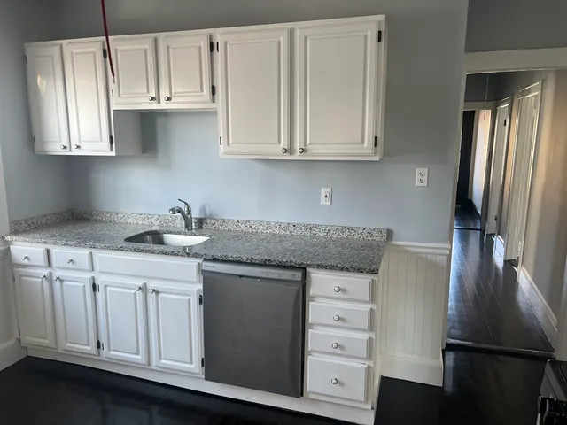 a kitchen with granite countertop white cabinets and stainless steel appliances
