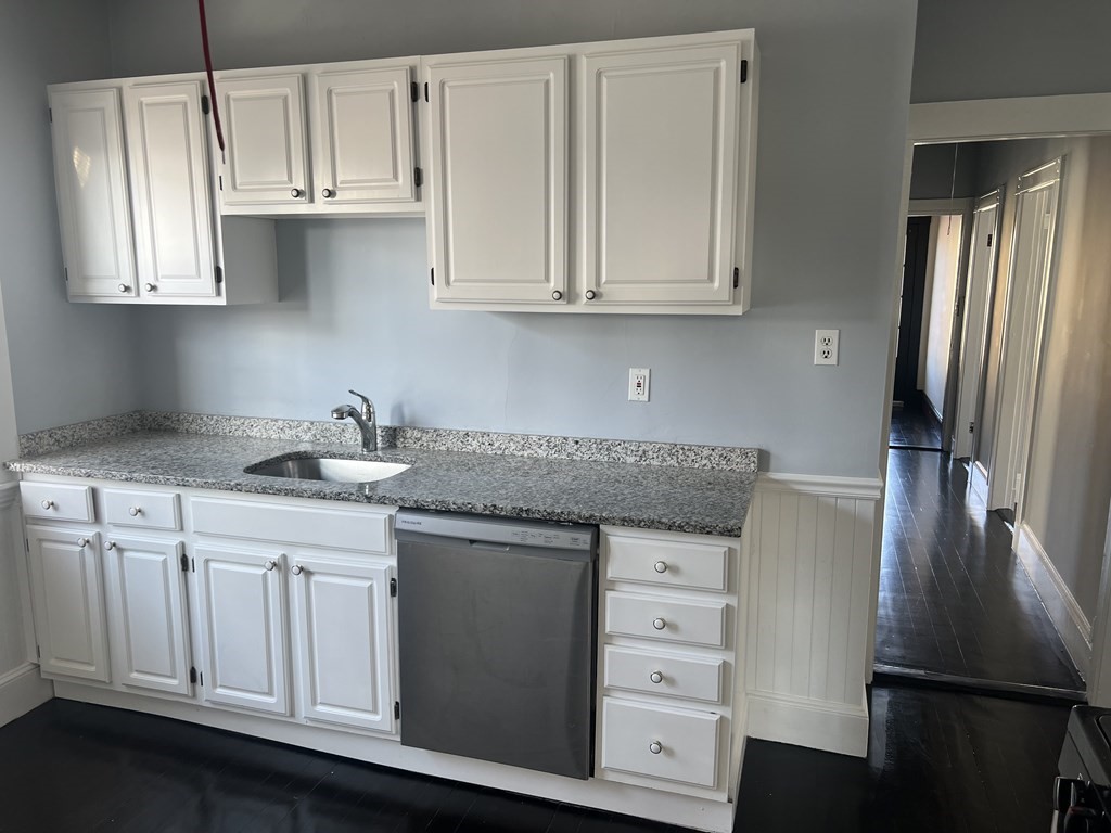a kitchen with granite countertop white cabinets and stainless steel appliances