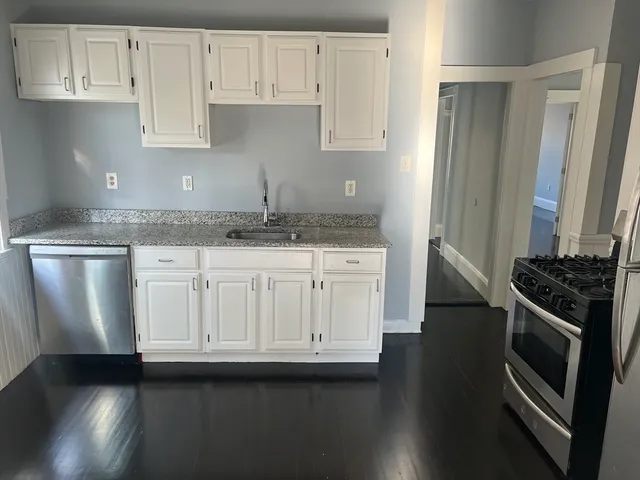 a kitchen with granite countertop white cabinets and stainless steel appliances