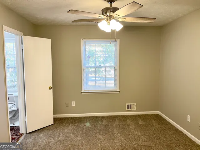 an empty room with windows and fan