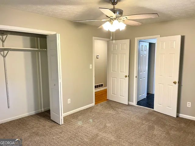 an empty room with closet and a ceiling fan